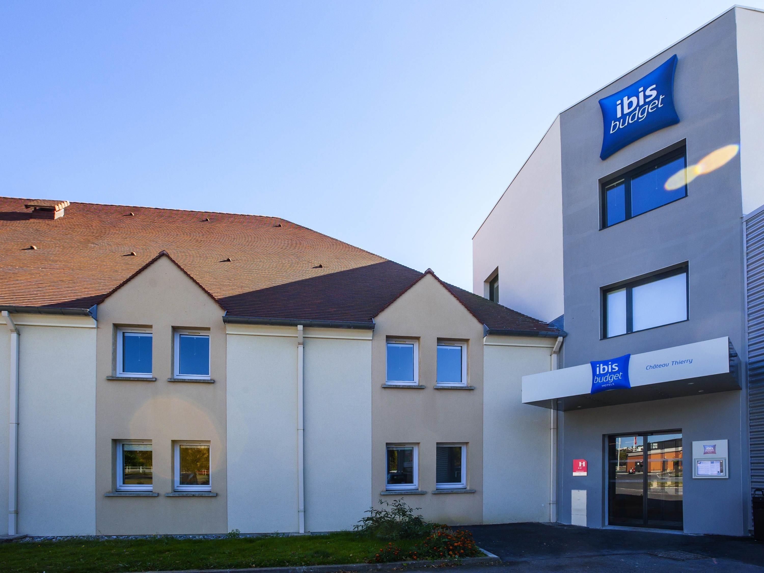 A modern hotel building with a flat roof and a sign for ibis budget.