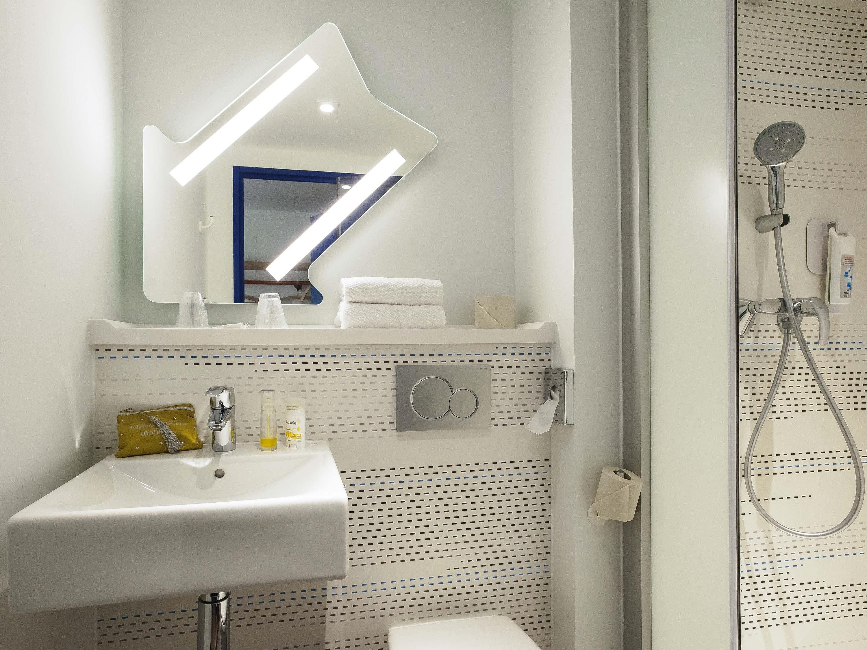 A bathroom with a sink, mirror, towel rack, and shower.