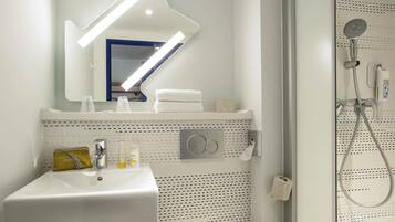 A bathroom with a sink, mirror, towel rack, and shower.