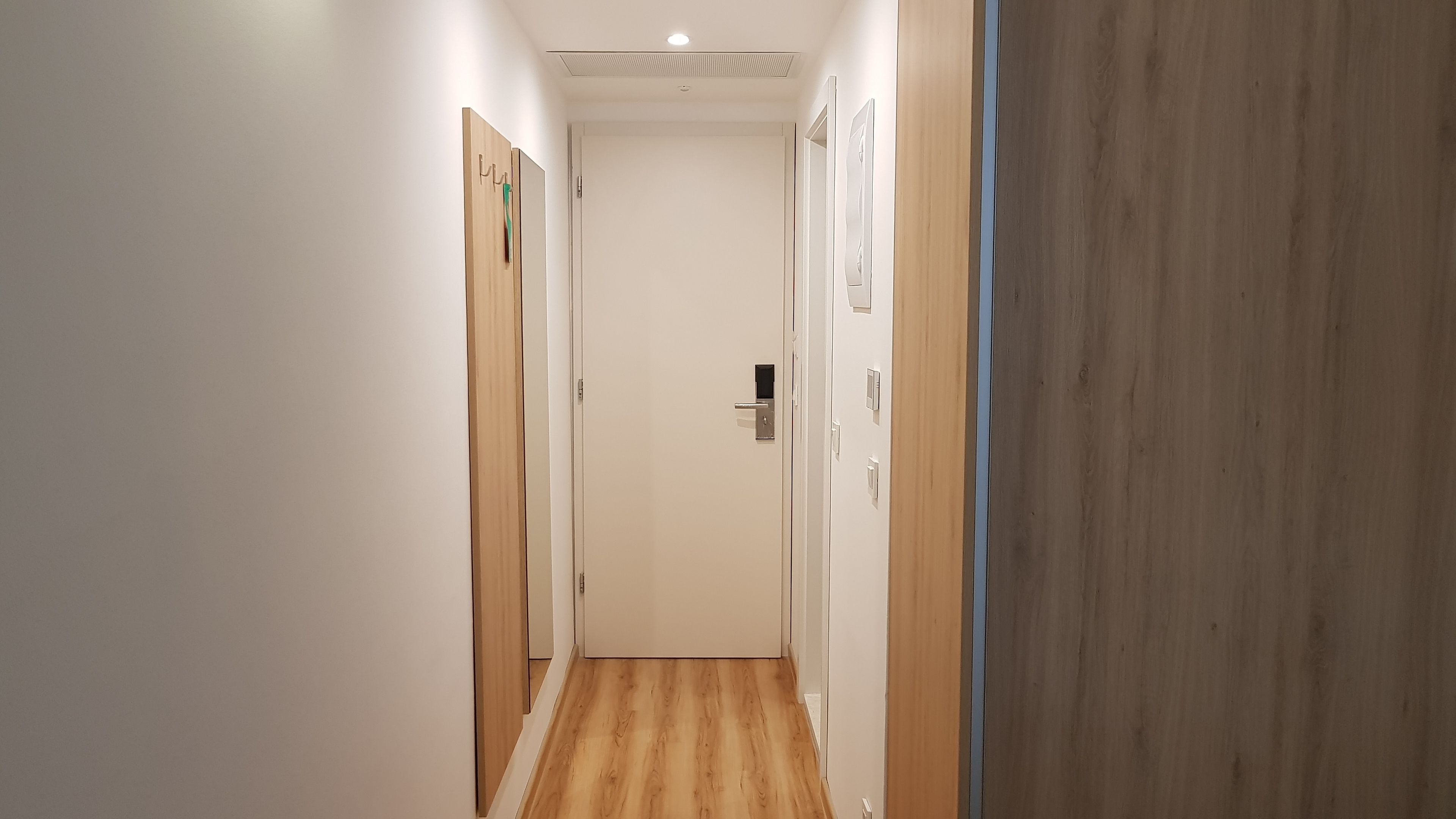 A narrow hallway with wooden flooring and white walls.