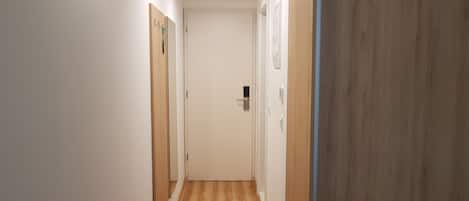 A narrow hallway with wooden flooring and white walls.