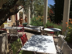 An outdoor patio area with tables and chairs, surrounded by plants and flowers. - Hôtel La Roselière (Saint-Quentin-Fallavier)