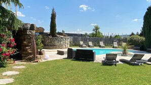 A backyard with a swimming pool, stone walls, and outdoor furniture. - Hôtel La Roselière (Saint-Quentin-Fallavier)