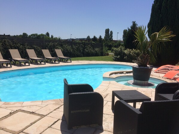 A swimming pool with lounge chairs and a potted plant. - Hôtel La Roselière (Saint-Quentin-Fallavier)