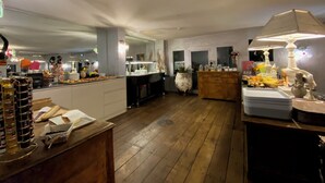A spacious kitchen with wooden flooring, white cabinets, and a central island. There are various kitchen appliances and a large window providing natural light. - Hôtel La Roselière (Saint-Quentin-Fallavier)