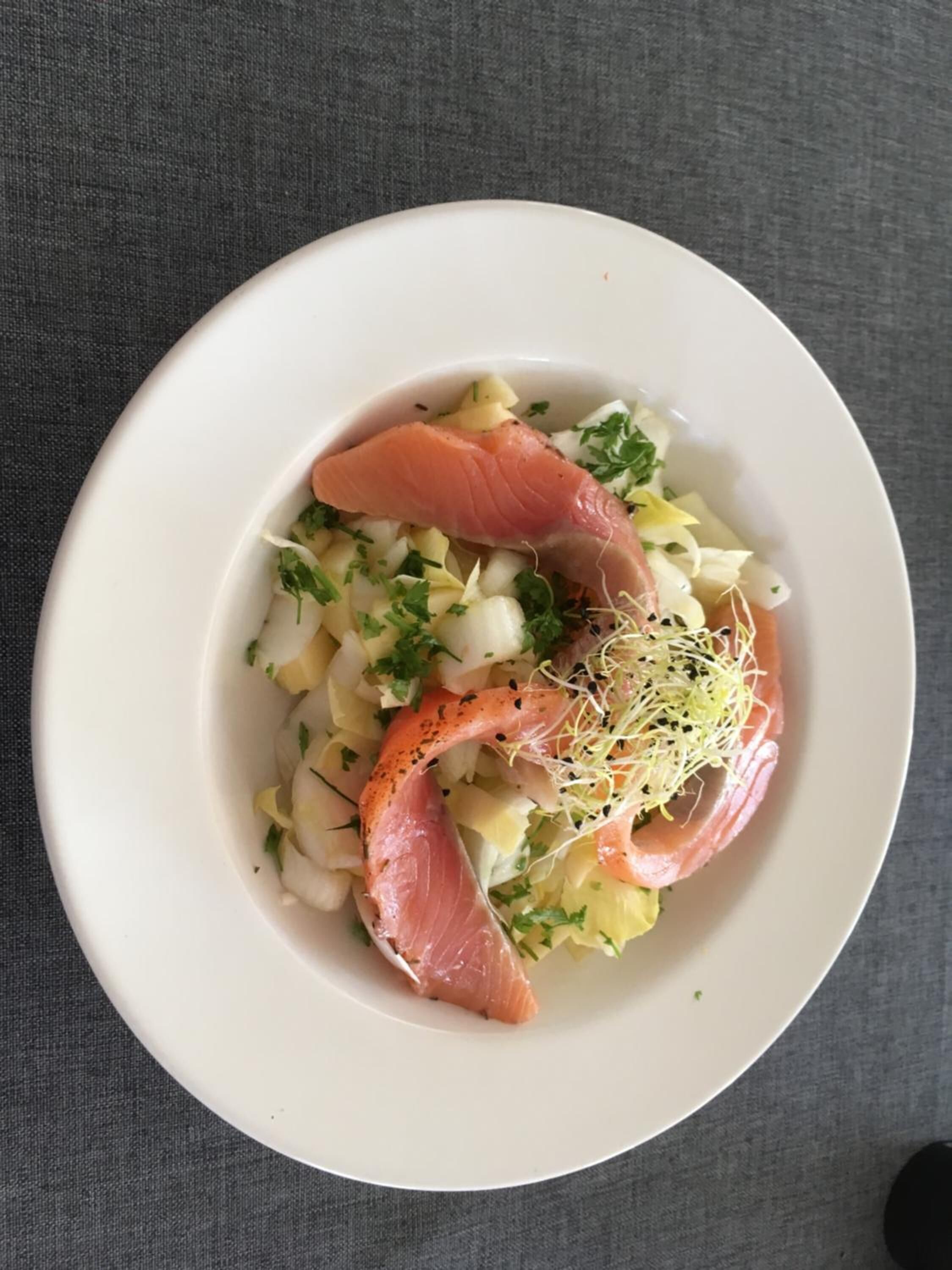 Ein weißer Teller mit Lachs, Kartoffeln und Grünzeug.