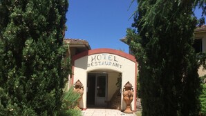 A hotel entrance with a sign reading "HOTEL RESTAURANT" and a pathway leading to the door. - Hôtel La Roselière (Saint-Quentin-Fallavier)