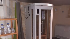 A room with a corner shower enclosure, a shelf with towels, and a bed.
