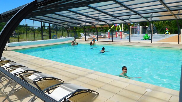Una piscina con zona techada y sillas de descanso.