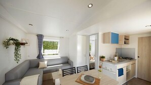 Un espacio habitable compacto con comedor, kitchenette y un sofá gris.
