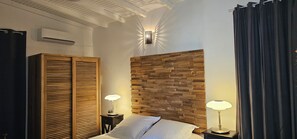 A bedroom with a wooden headboard, two bedside lamps, a wardrobe, and a ceiling fan. - Habitation Villa Les Cassias (Petit-Bourg)