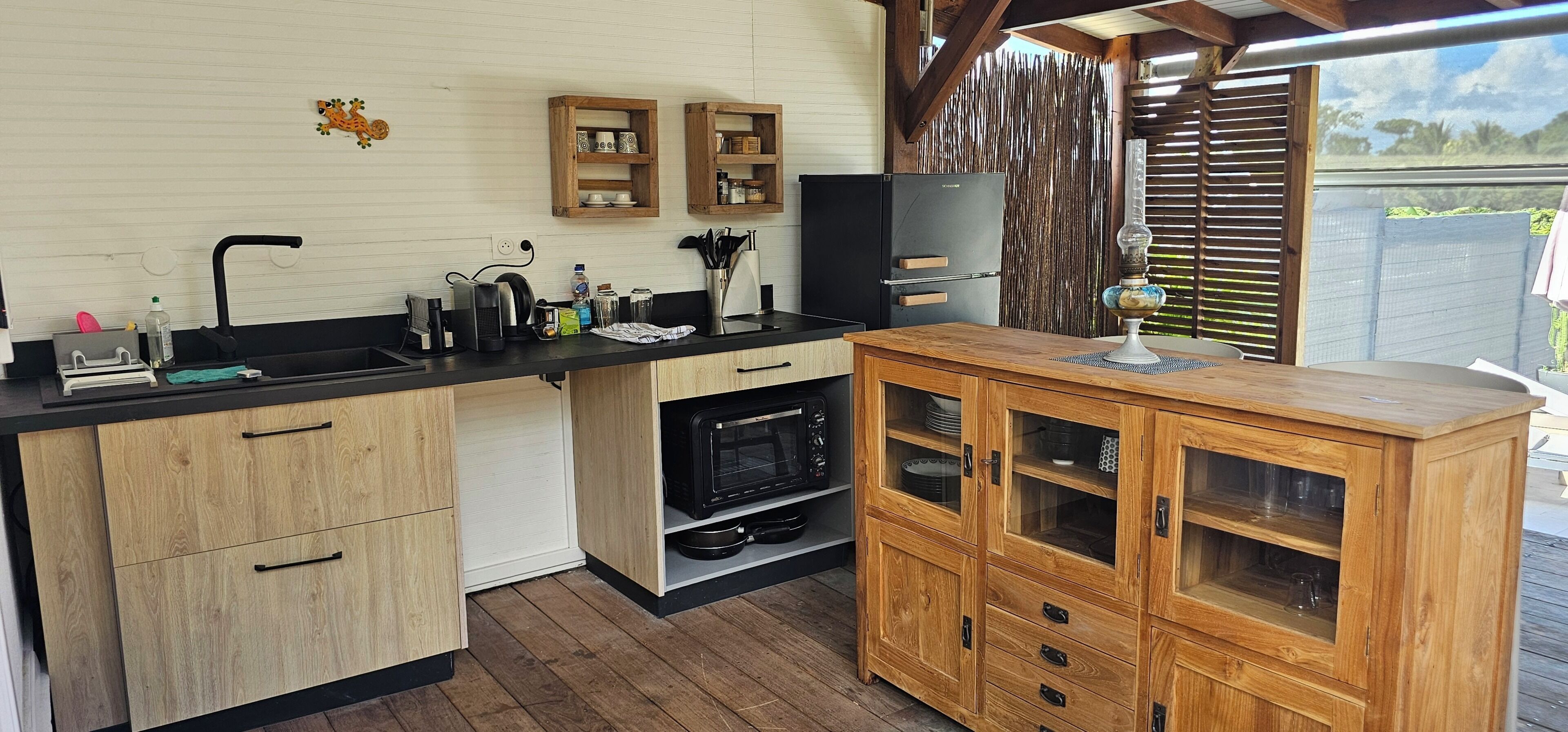 Una cocina con armarios de madera, encimera negra y horno empotrado.