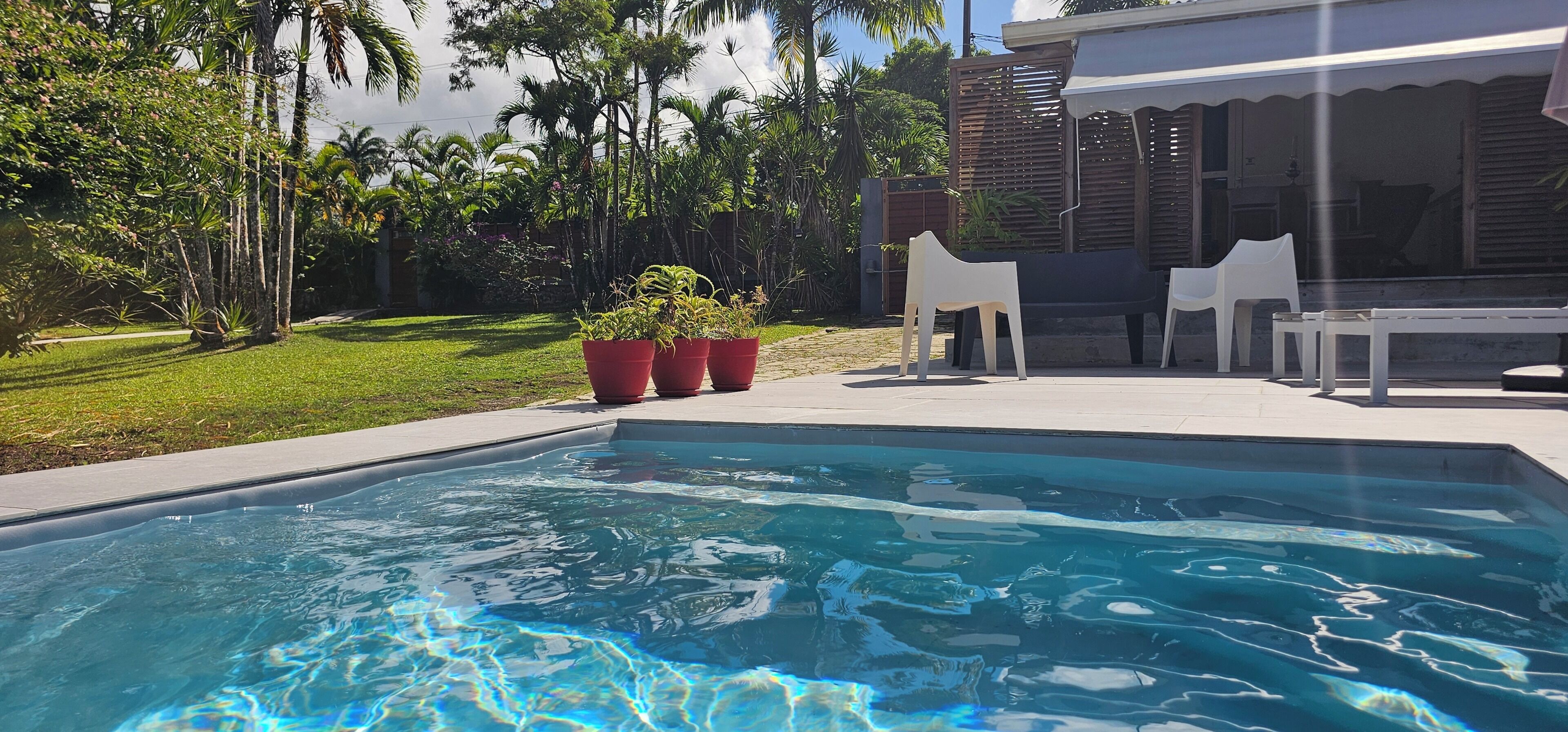 A swimming pool with a clear blue water surface, surrounded by a grassy area and trees.
