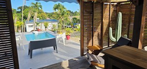 Un área de piscina con terraza de madera, sillas de descanso y plantas en macetas.