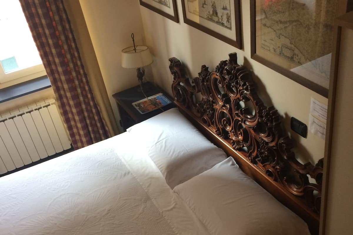 A hotel room with a large bed, a wooden headboard, and three framed pictures on the wall.