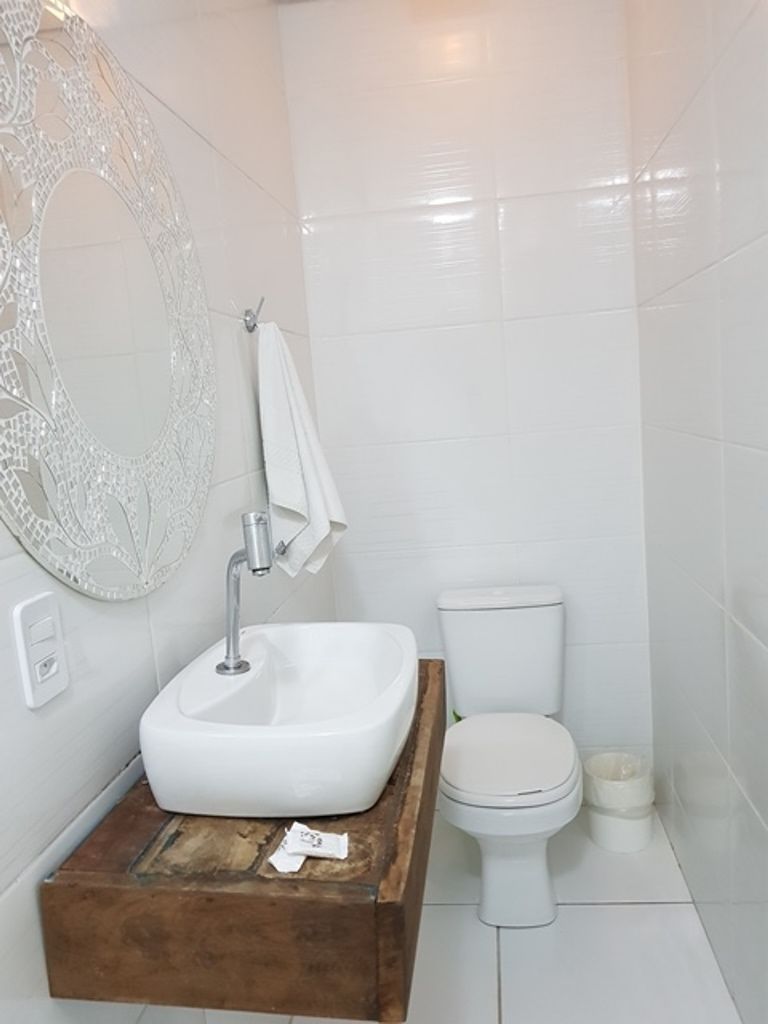 A bathroom with a white sink, toilet, and a decorative mirror.