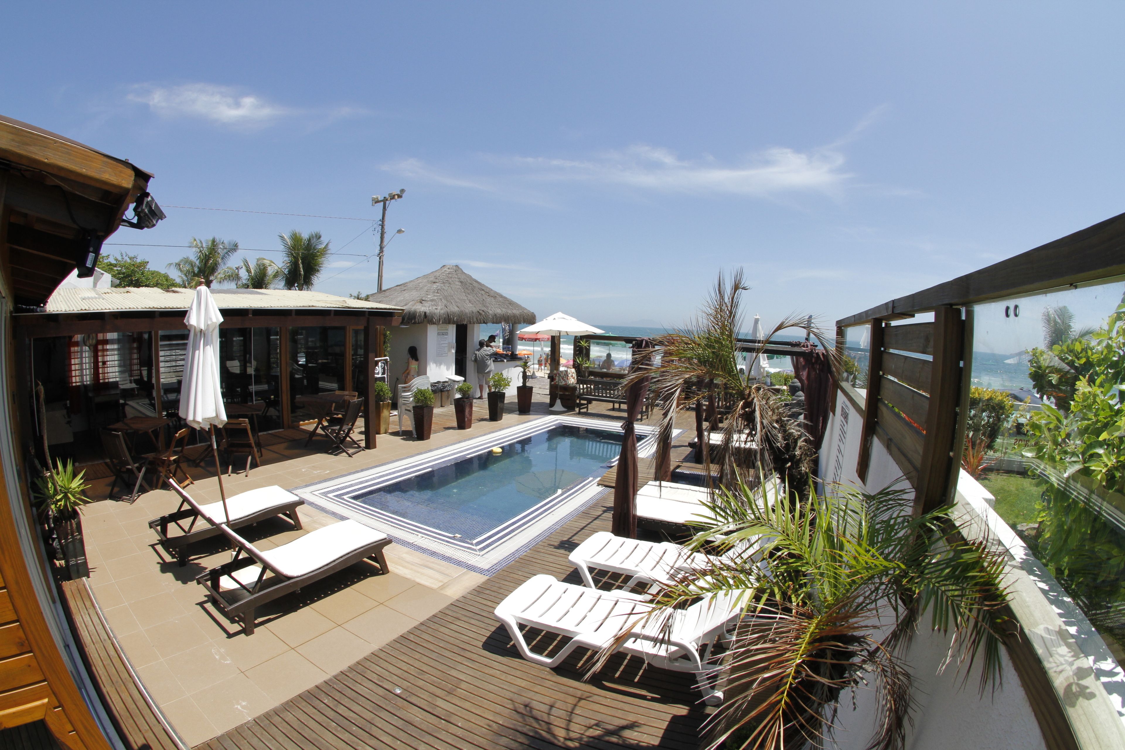 A rooftop pool area with lounge chairs, a pool, and a view of the ocean.