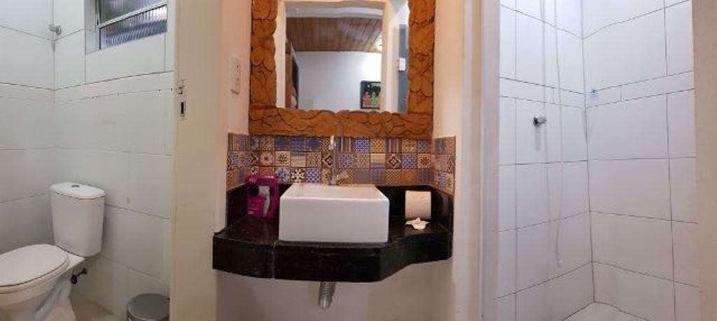A bathroom with a white toilet, a sink with a mirror above it, and a shower area.