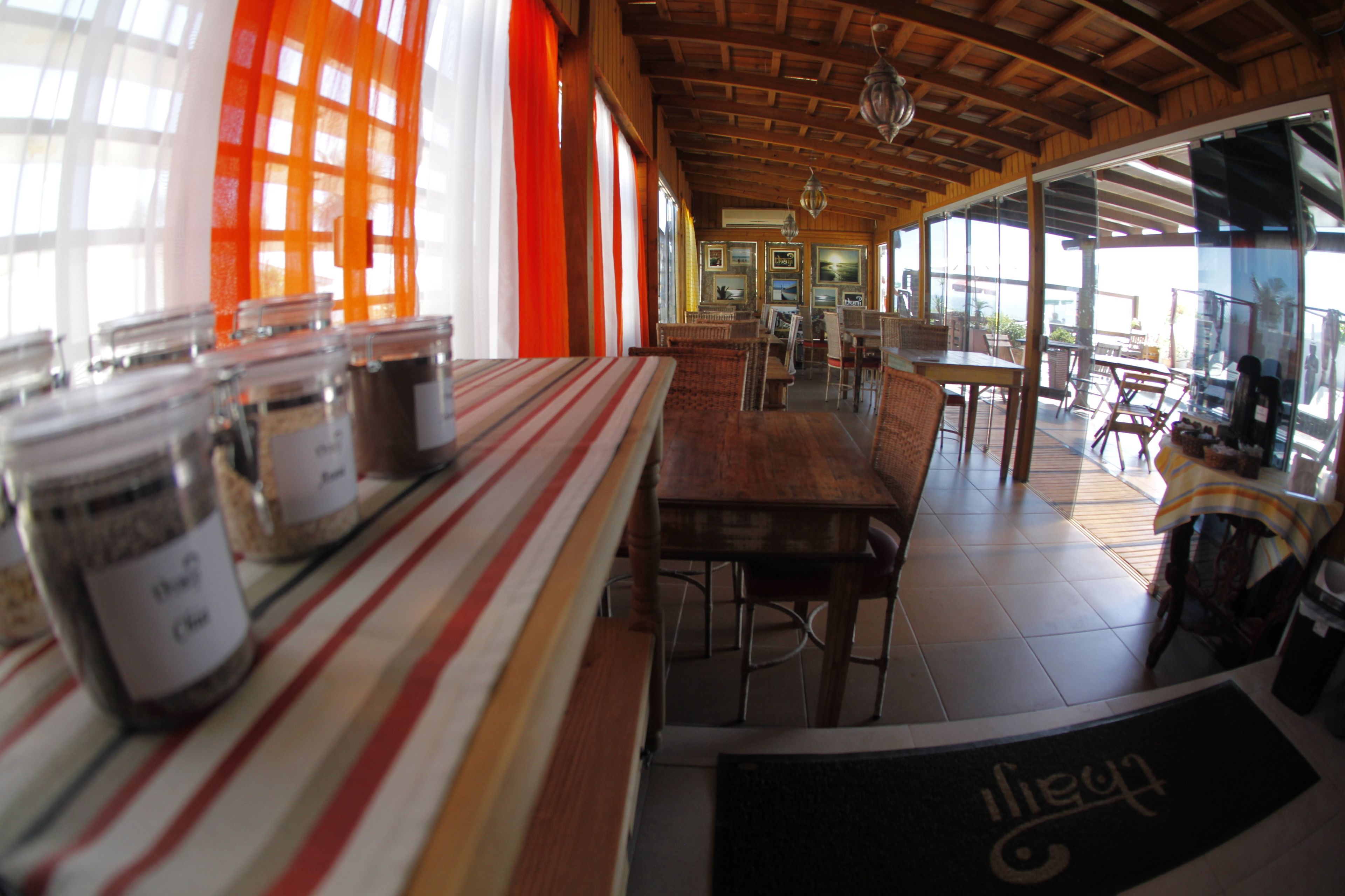 A restaurant with a long counter, wicker chairs, and a view through large windows.