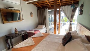 A hotel room with a wooden ceiling, a large bed with white and orange bedding, a small table with a statue, and a window with curtains. - Thaiji Pousada e Parador (Florianópolis)