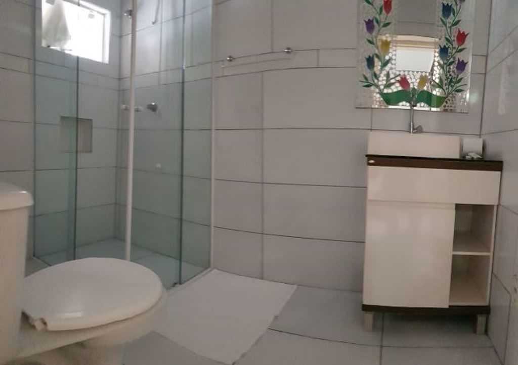 A bathroom with a glass-enclosed shower, a white toilet, and a sink with a mirror above it.