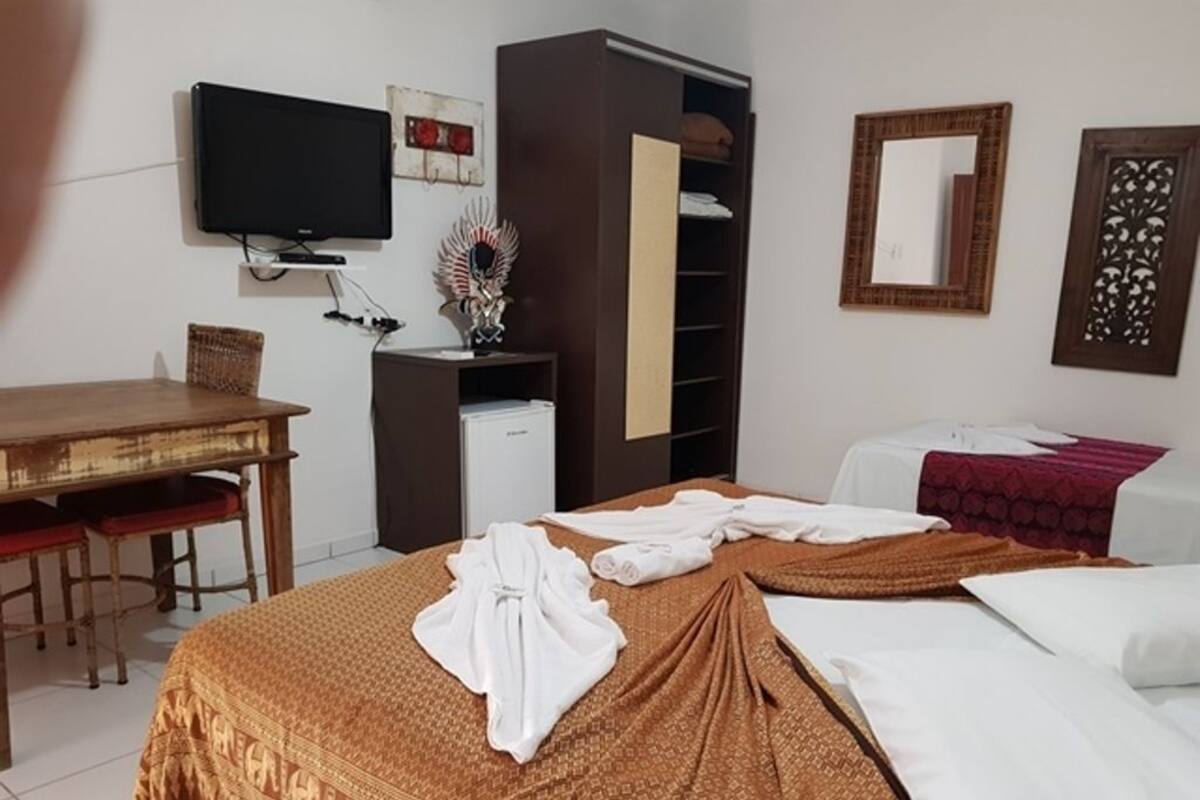 Habitació d'hotel amb llit, escriptori, televisió i armari.