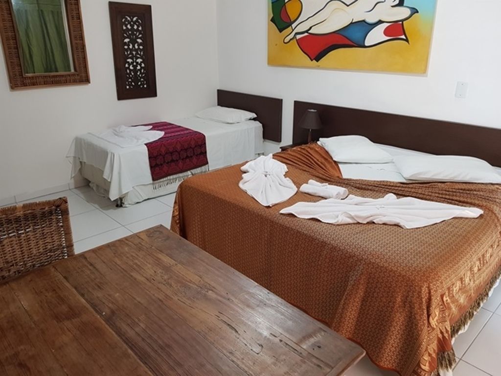 Una camera d'albergo con due letti, un tavolo in legno e un quadro appeso al muro.