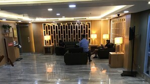 A spacious lobby with a marble floor, a reception desk, and a seating area with lamps. - Sudirman Park Apartment by Merry (Jakarta)