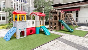 A children's play area with a slide, climbing structures, and a small house with a slide. - Sudirman Park Apartment by Merry (Jakarta)