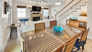 A spacious living area with a dining table, chairs, a sofa, and a staircase.