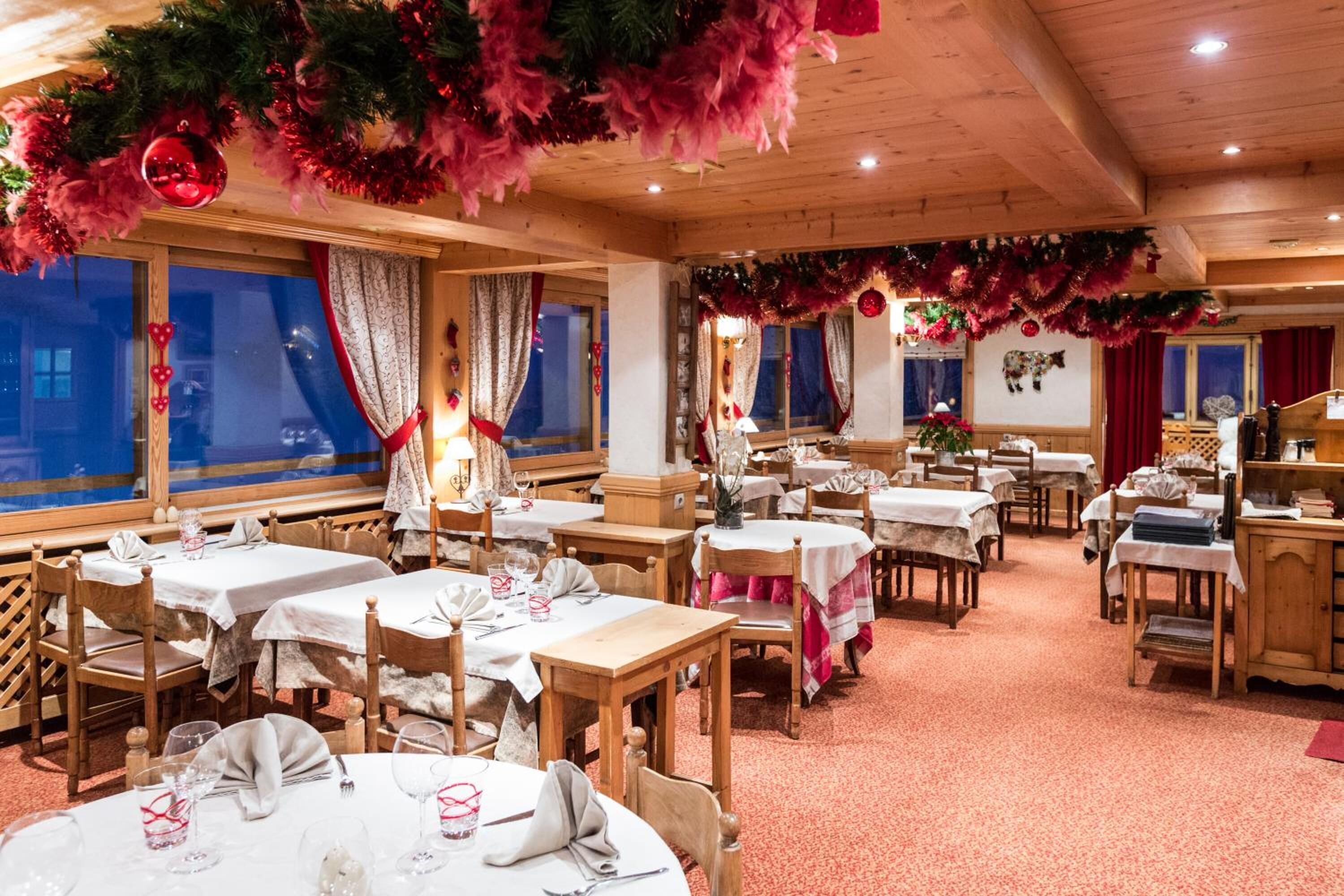 Een gezellig restaurant met houten tafels en stoelen, feestelijke decoraties en een warme inrichting.