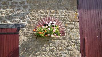 A stone wall with a flower box containing pink, orange, and white flowers.