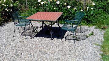 An outdoor seating area with a table and chairs, surrounded by gravel and greenery.