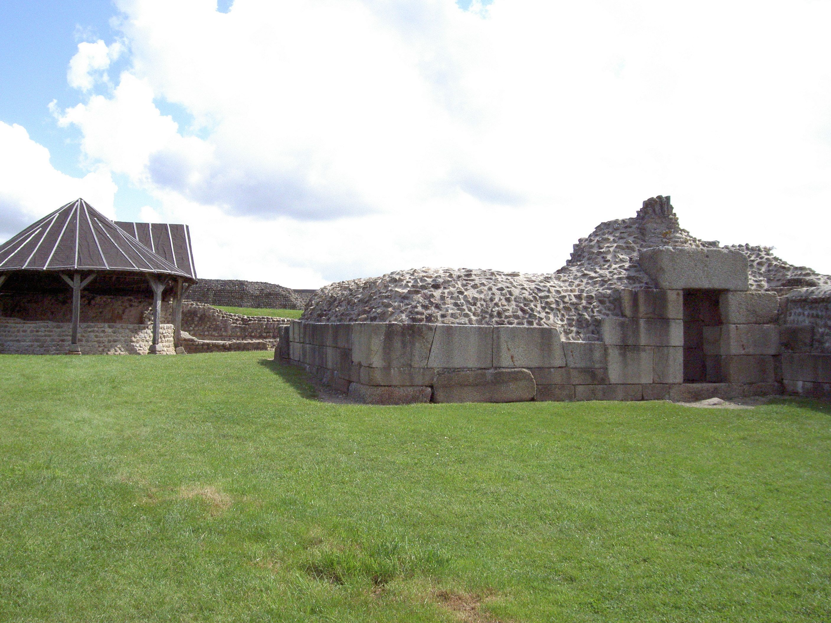 Una antigua estructura de piedra con techo en forma de pirámide y una pared de piedra con una entrada.