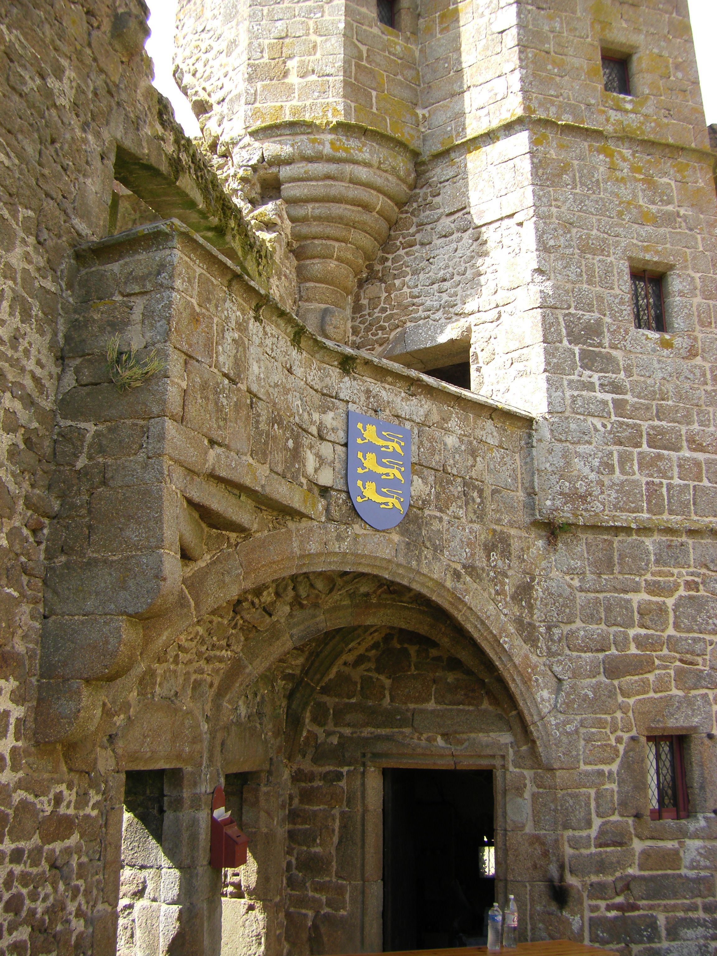 A stone building with a prominent archway and a coat of arms above it.