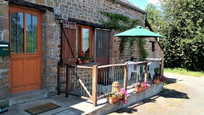 A stone building with a wooden door, a window with a curtain, and a balcony with a railing.