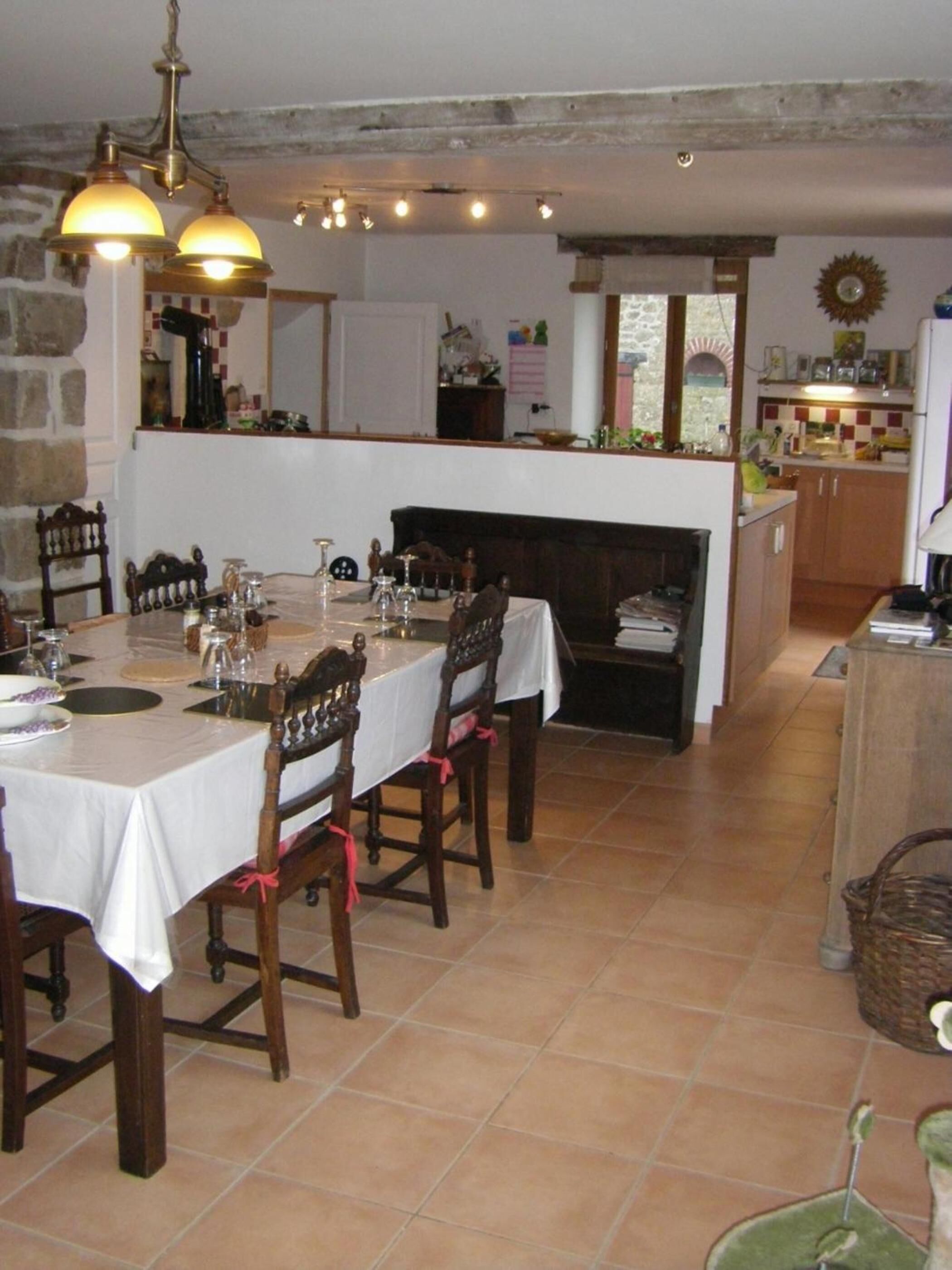 Uma sala de jantar com uma mesa comprida para seis pessoas, cadeiras de madeira e um lustre.
