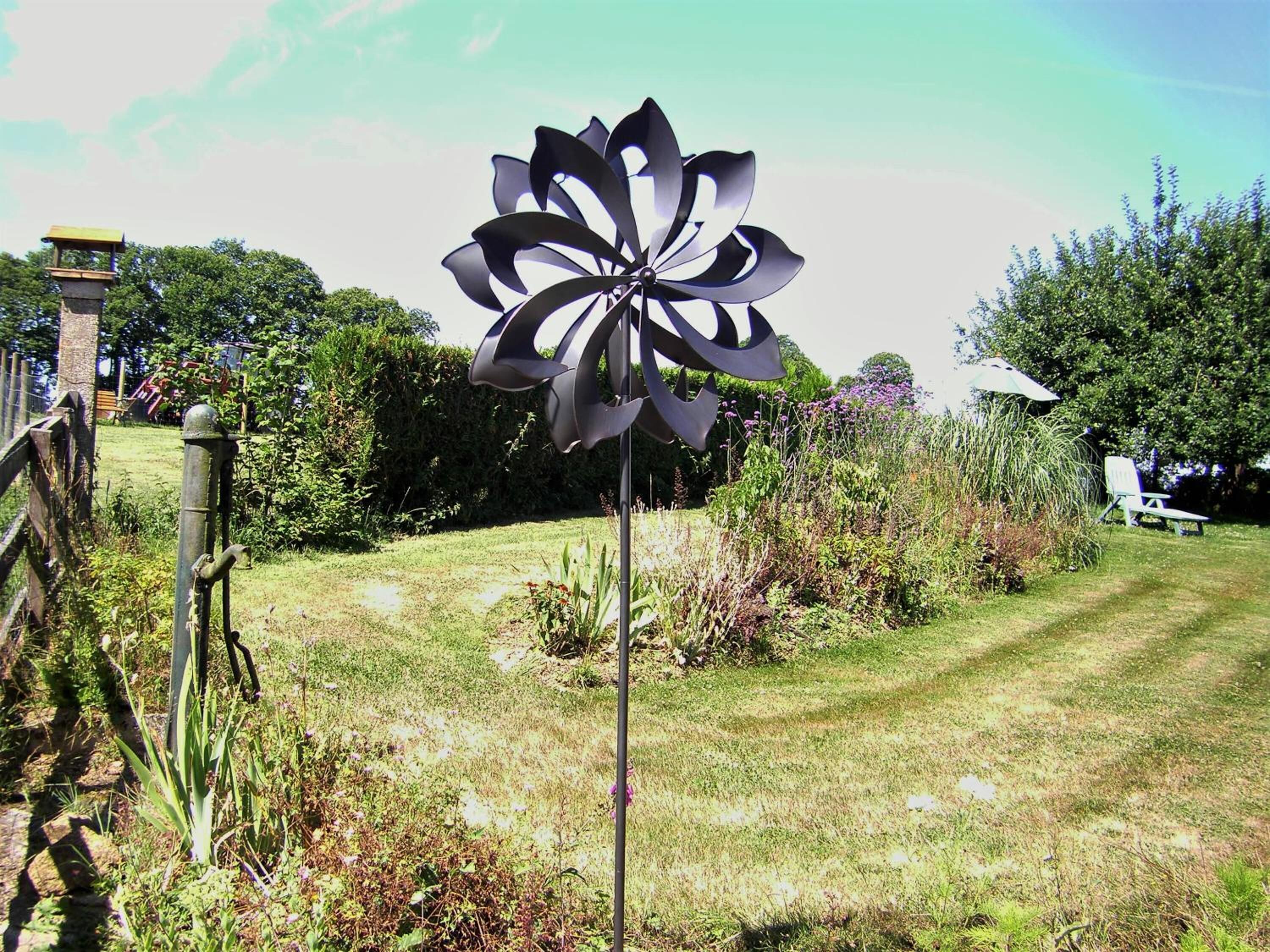 A garden with a windmill-like structure, a wooden fence, and a bench.