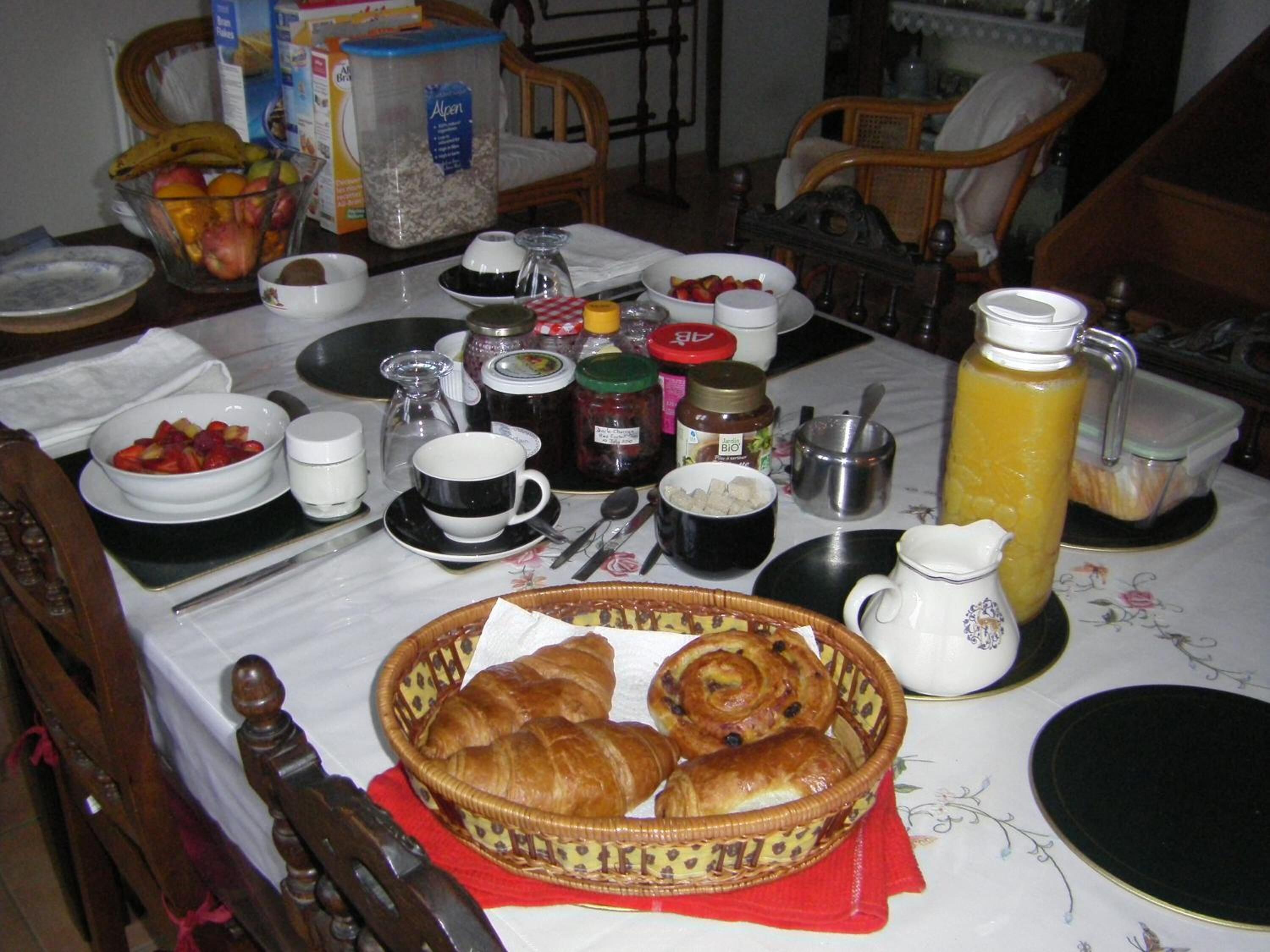 A breakfast table with various food items, including fruits, pastries, and beverages.