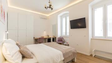 Un dormitorio moderno con cama, armario, escritorio, silla y televisor montado en la pared.