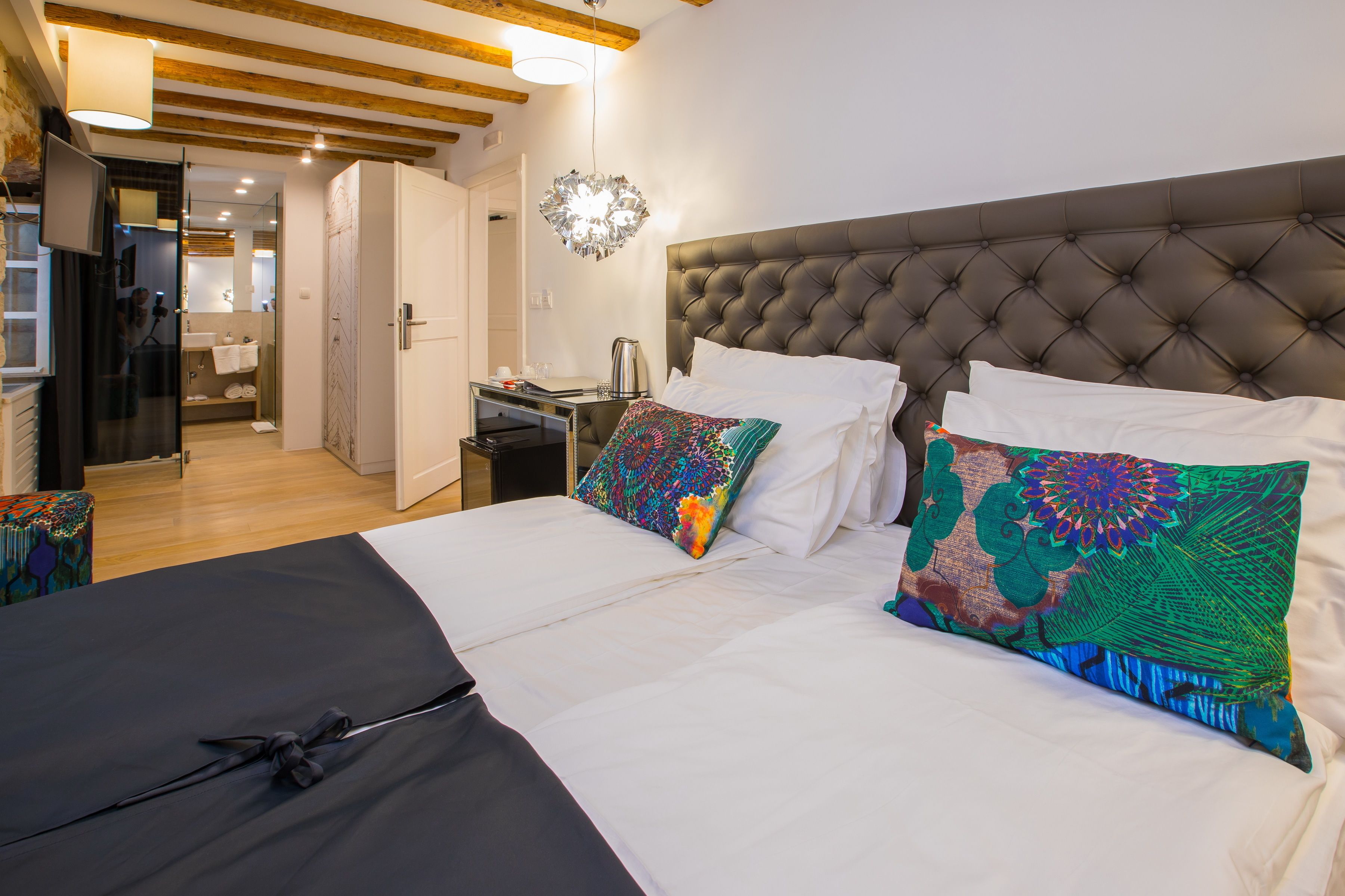 A hotel room with a large bed, two pillows, a bedside table, and a mirror.