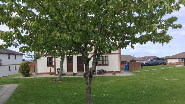 A residential area with a house, a lawn, and a parked car. - One bedroom Wyvis (Inverness)