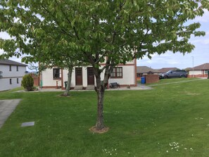 A residential area with a house, a lawn, and a parked car. - One bedroom Wyvis (Inverness)