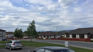 A residential street with houses, a car, and a tree. - One bedroom Wyvis (Inverness)