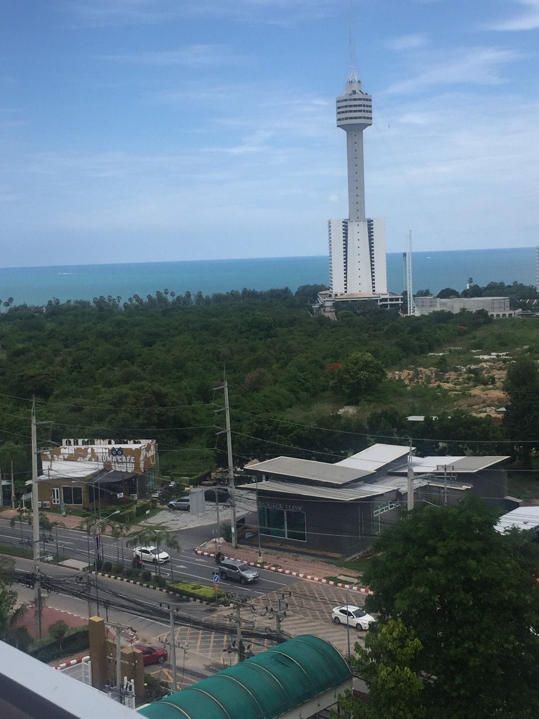 A view of a cityscape with a prominent tower, a clinic, and a road with vehicles.