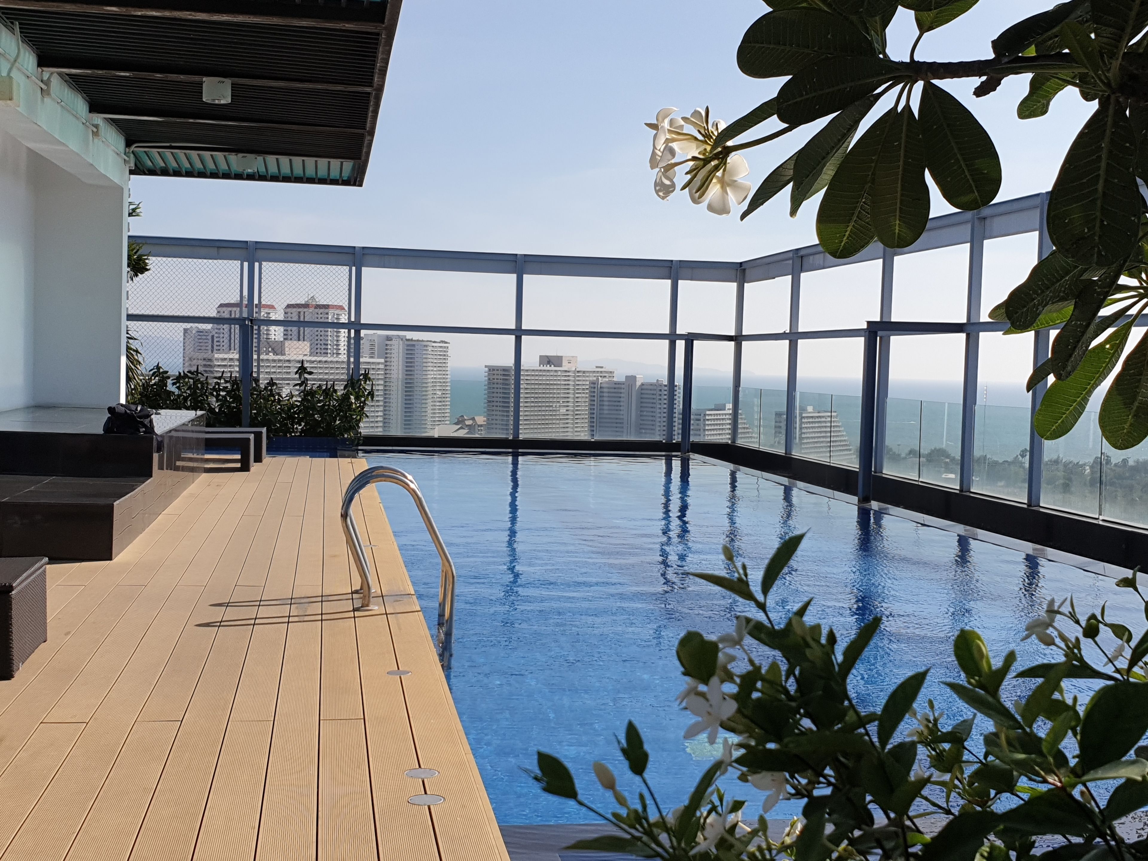 An indoor infinity pool with a wooden deck, surrounded by large windows offering a city view.