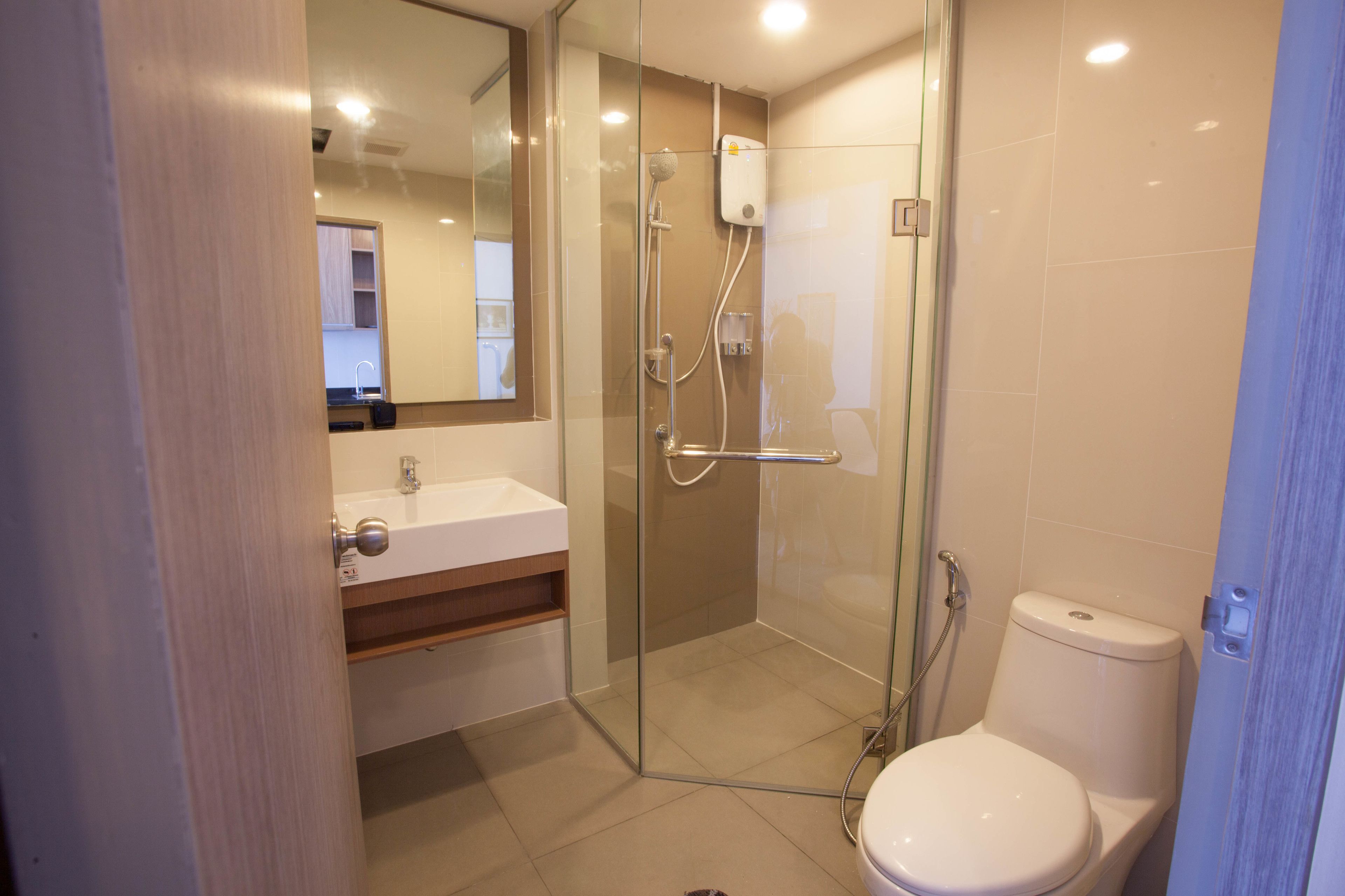 A modern bathroom with a glass-enclosed shower, a white toilet, and a sink with a mirror above it.