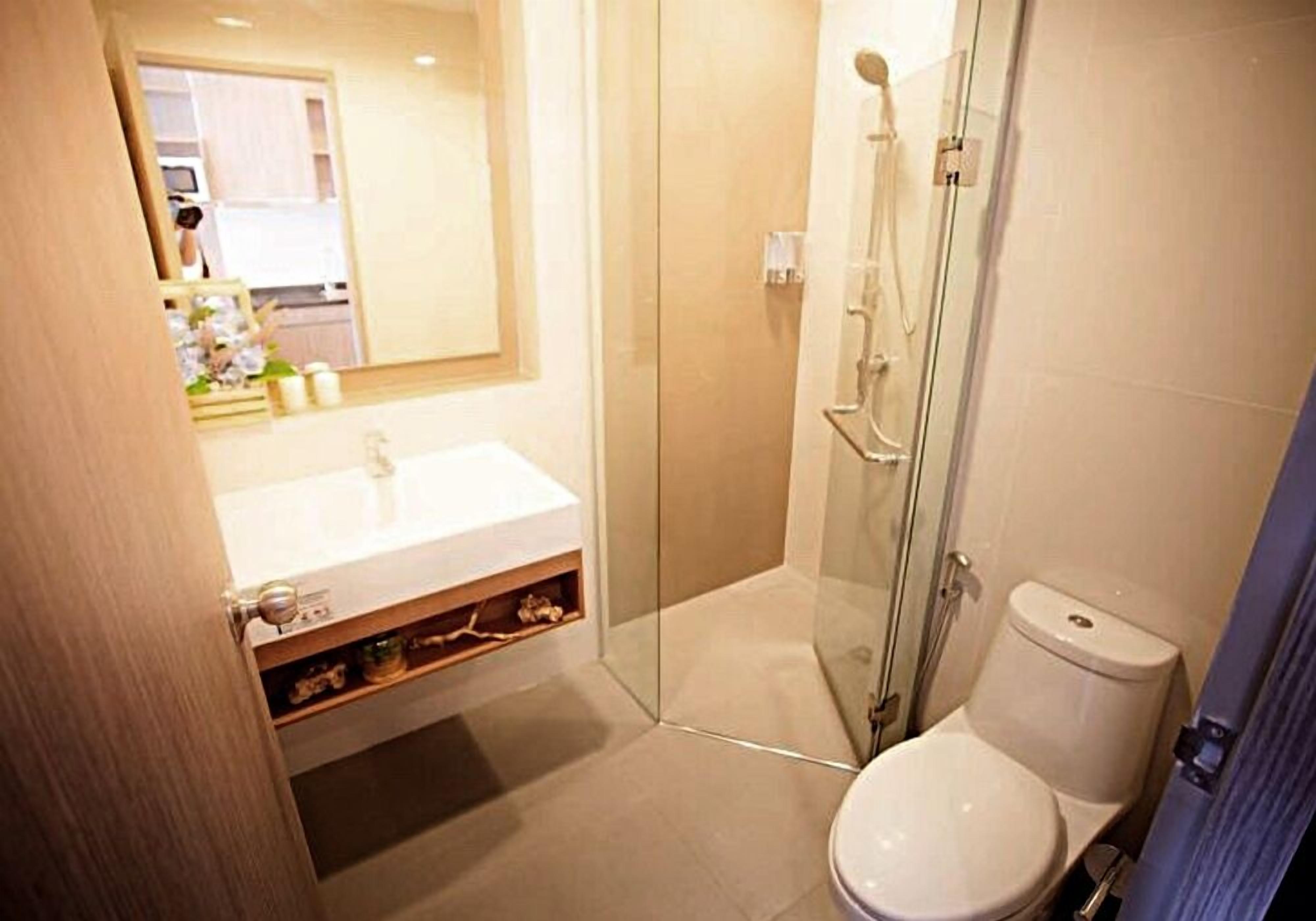 A modern bathroom with a glass-enclosed shower, a white toilet, and a sink with a mirror above it.