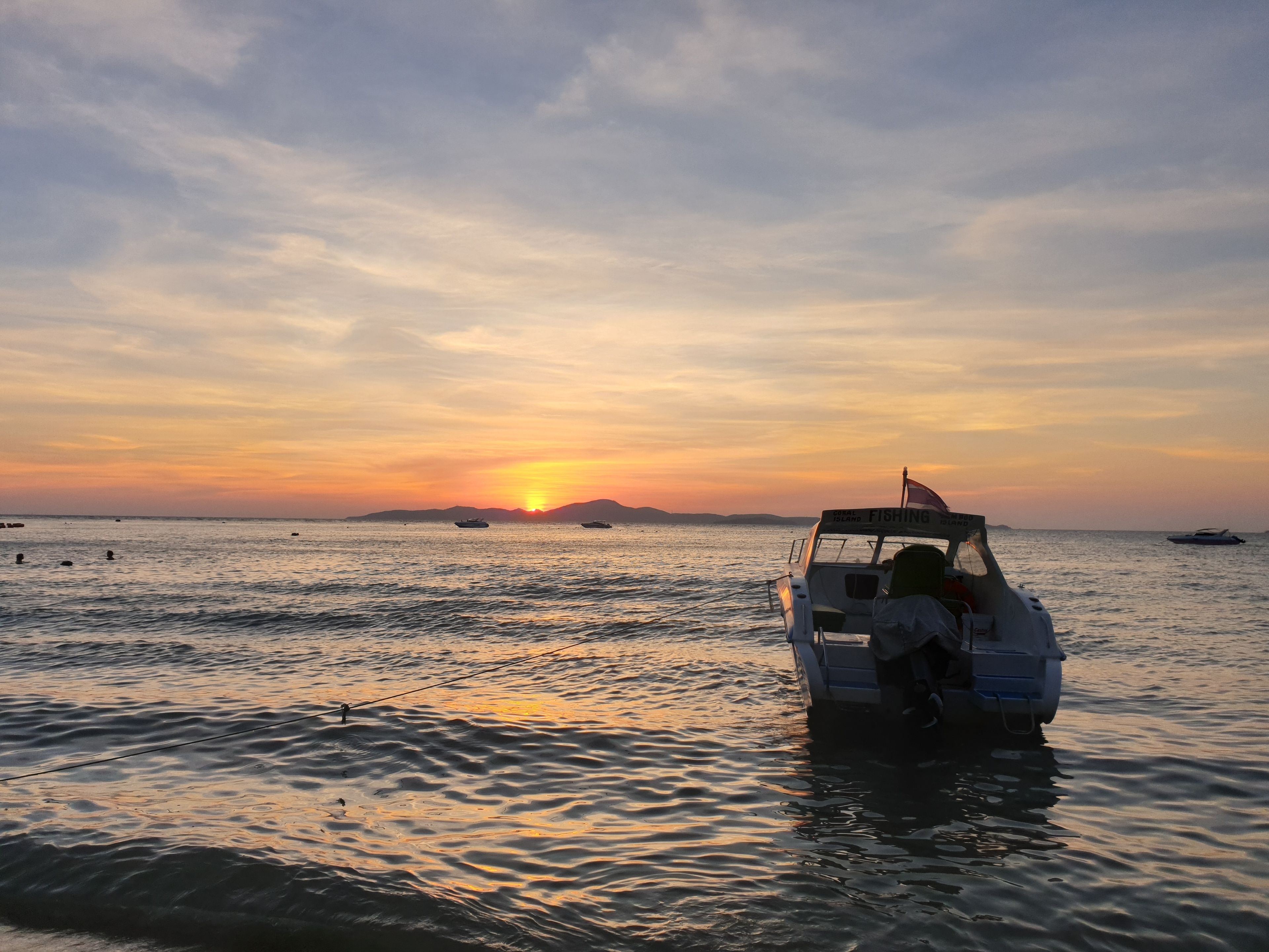 A boat docked at a pier with a sunset in the background.