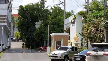 Una calle con coches aparcados, un edificio con un cartel que dice 'OUT' y una estatua.